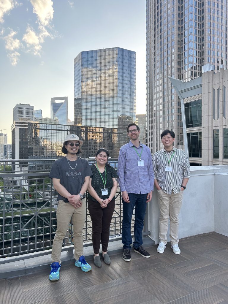University of Washington PhD students and faculty stand in front of the Charlotte, NC skyline.