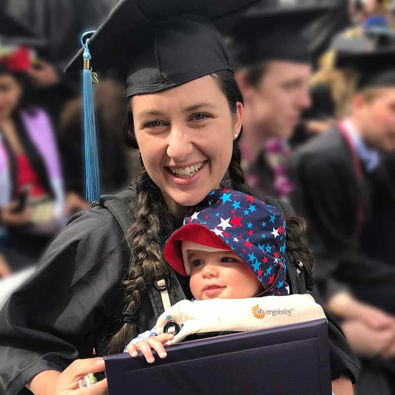 Heather White holding diploma and new born baby during graduation ceremony
