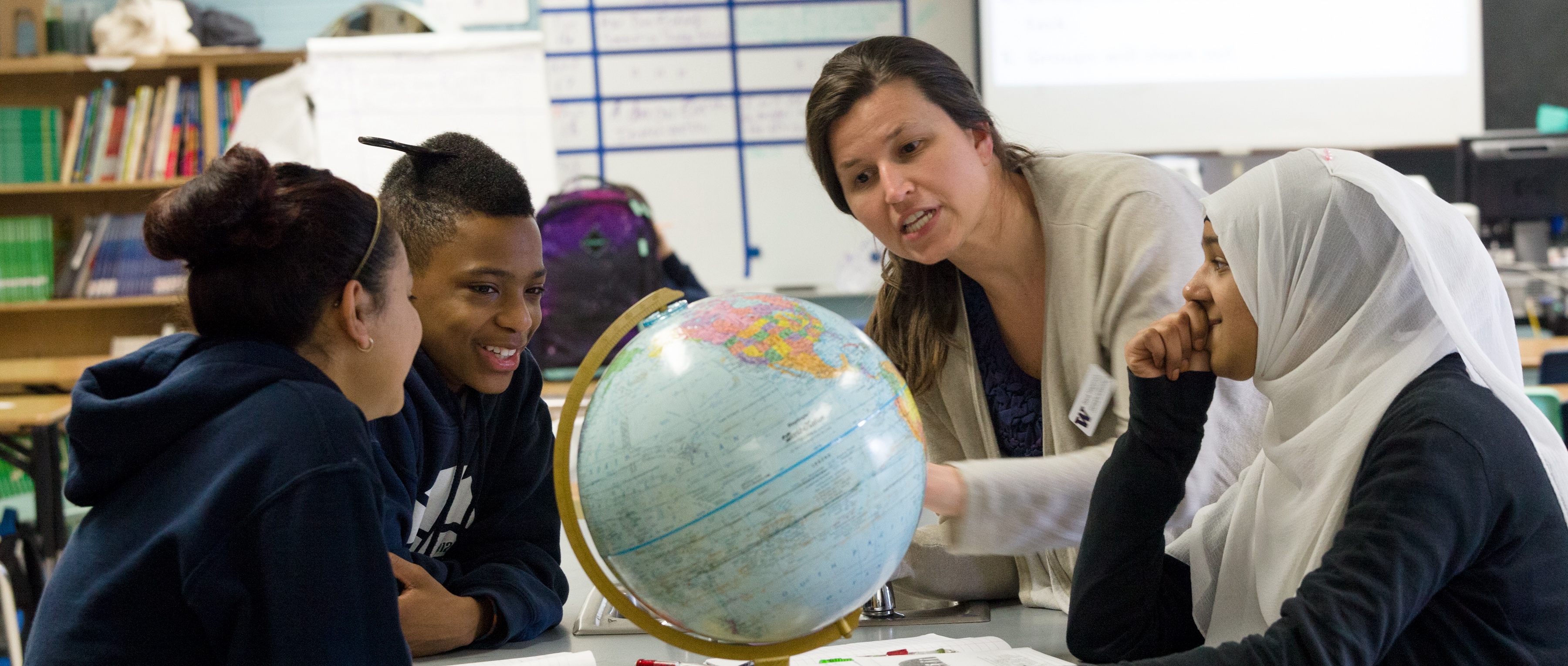 teacher and students looking at a globe